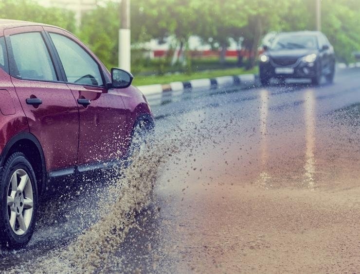 une voiture rouge roulant sur une route mouillée